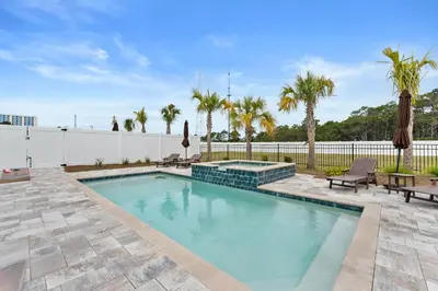 a swimming pool in a yard with a fence and palm trees at Beach House - Sugary Sands by Panhandle Getaways in Panama City Beach