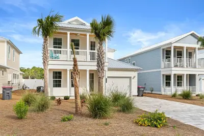 a white house with palm trees in front of it at Pet Friendly Beach House - Sugary Sands by Panhandle Getaways in Panama City Beach