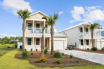 a white house with palm trees in front of it at Pet Friendly Beach House - Sugary Sands by Panhandle Getaways in Panama City Beach