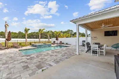 a patio with a pool and a table and chairs at Pet Friendly Beach House - Sugary Sands by Panhandle Getaways in Panama City Beach