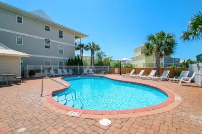 a swimming pool with chairs and a building at Beachside Villas 933 in Santa Rosa Beach