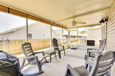 a screened porch with chairs and a ceiling fan at Panama City Vacation Rental with 2 Community Pools! in Panama City Beach