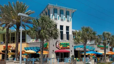 a building with palm trees and umbrellas in front of it at A Salty Cru in Panama City Beach