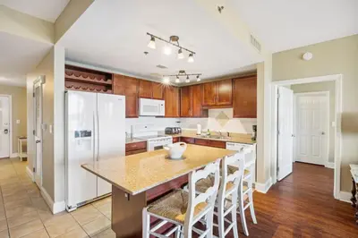 a kitchen with wooden cabinets and a large island with bar stools at Laketown Wharf #1230 by Nautical Properties Vacation Rentals in Panama City Beach