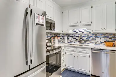 a kitchen with white cabinets and a refrigerator at Walk to Beach! PCB Resort Condo with Pool Access in Panama City Beach