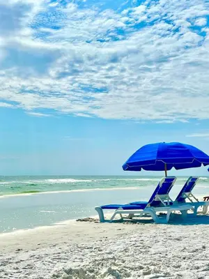 a pair of chairs and an umbrella on a beach at Beach access close to Walmart, Bowling,skating and Game room in Panama City Beach