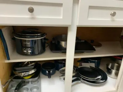 a kitchen cabinet with pots and pans on a shelf at Beach access close to Walmart, Bowling,skating and Game room in Panama City Beach