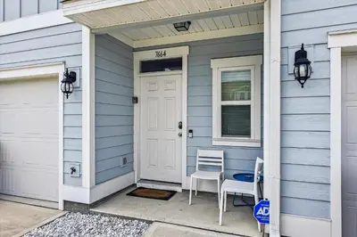a blue house with a white door and two chairs at 7664 Shadow Lake - Happy Horizons - 3 Bedroom Sleeps 9 townhouse in Panama City Beach