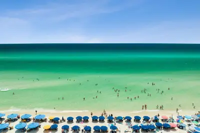 a group of people on a beach with umbrellas at 30A Villas at Sunset Beach by Panhandle Getaways in Rosemary Beach