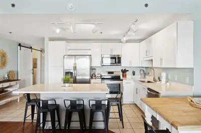 a kitchen with white cabinets and a large island with bar stools at Laketown Wharf #333 by Nautical Properties in Panama City Beach