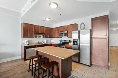 a kitchen with wooden cabinets and a stainless steel refrigerator at Laketown Wharf #2136 by Nautical Properties in Panama City Beach
