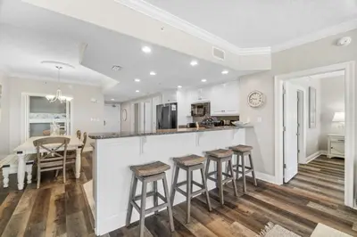 a kitchen with white cabinets and bar stools at Treasure Island #1008 in Panama City Beach