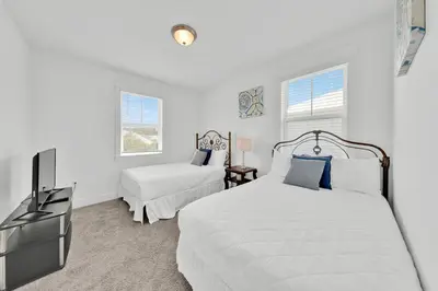 a white bedroom with two beds and a tv at Grande Pointe Sea Shell in Inlet Beach