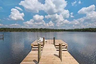 a wooden dock on a lake with clouds in the sky at Grande Pointe Sea Shell in Inlet Beach