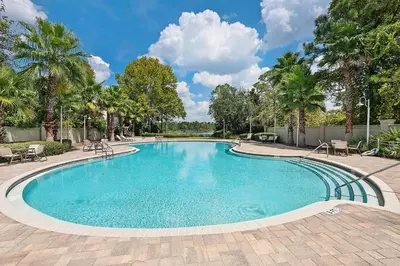 a swimming pool with chairs and palm trees at Grande Pointe Sea Shell in Inlet Beach