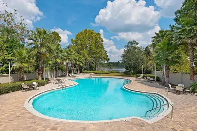 a swimming pool with tables and chairs and palm trees at Grande Pointe Sea Shell in Inlet Beach