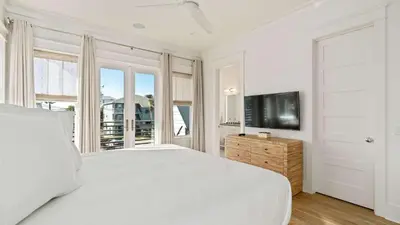 a white bedroom with a large bed and a tv at 30A Beach Therapy in Inlet Beach
