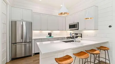 a kitchen with white cabinets and a sink and stools at 30A Beach Therapy in Inlet Beach