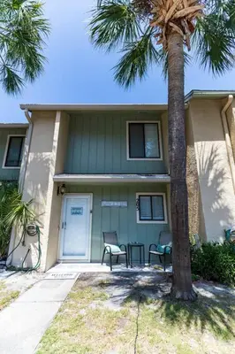 a house with two chairs and a palm tree at Spacious Family Hideaway on the Emerald Coast! in Panama City Beach