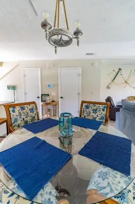 a dining room with a glass table and blue mats at Spacious Family Hideaway on the Emerald Coast! in Panama City Beach