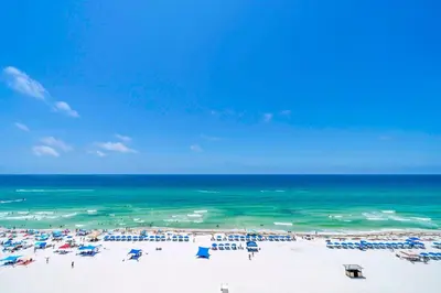 a beach with chairs and umbrellas and the ocean at Long Beach Resort 1-904 in Panama City Beach