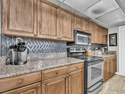 a kitchen with wooden cabinets and a stove top oven at Long Beach Resort 1-904 in Panama City Beach