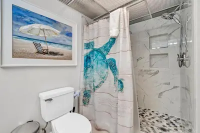 a bathroom with a shower curtain with a picture of a beach at Long Beach Resort 1-904 in Panama City Beach