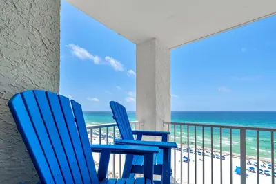 two blue chairs on a balcony overlooking the beach at Long Beach Resort 1-904 in Panama City Beach