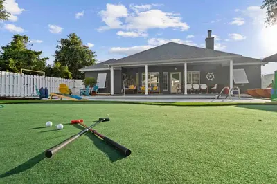 two baseball bats and balls on a lawn in front of a house at Luxurious 4BR Beach House with Pool in Panama City Beach