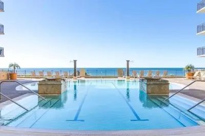 a swimming pool with the ocean in the background at Beautiful Beach Condo - luxury living at its best in Panama City Beach