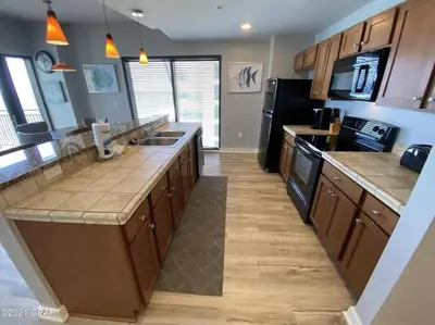 a kitchen with wooden cabinets and a black refrigerator at Beautiful Beach Condo - luxury living at its best in Panama City Beach