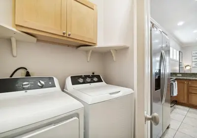 a kitchen with a washing machine and a refrigerator at Cozy Beach House (4 min walk) w/Pool + Fast WiFi in Panama City Beach