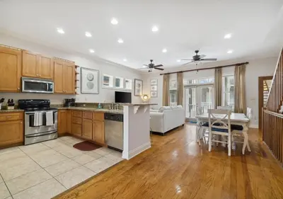 a kitchen with wooden cabinets and a dining room with a table at Cozy Beach House (4 min walk) w/Pool + Fast WiFi in Panama City Beach