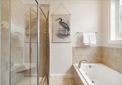 a bathroom with a tub and a bird picture on the wall at Cozy Beach House (4 min walk) w/Pool + Fast WiFi in Panama City Beach