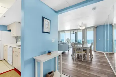 a kitchen and dining room with blue walls and a table and chairs at Long Beach Resort 3-404 in Panama City Beach