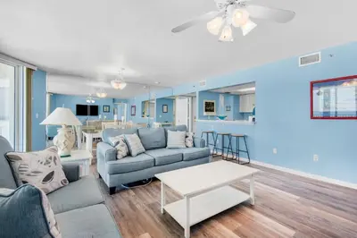a living room with blue walls and a couch and a table at Long Beach Resort 3-404 in Panama City Beach