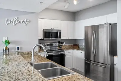 a kitchen with white cabinets and a stainless steel refrigerator at PCB Emerald beach retreat in Panama City Beach