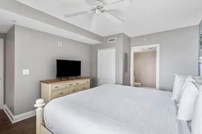 a bedroom with a bed and a flat screen tv at PCB Emerald beach retreat in Panama City Beach