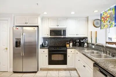 a kitchen with white cabinets and a stainless steel refrigerator at Treasure Island #1502 in Panama City Beach