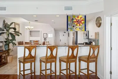 a kitchen with a bar with four stools at Treasure Island #1502 in Panama City Beach