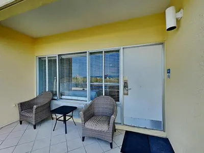 a balcony with two chairs and a table and windows at Continental 107 in Panama City Beach