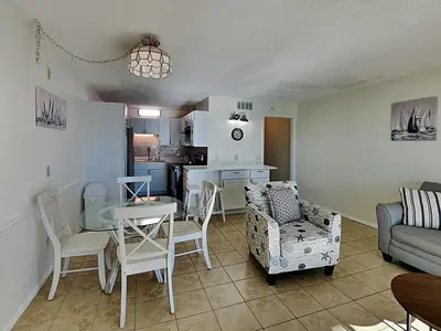a living room with a table and chairs and a kitchen at Summit Beach Resort #1102 in Panama City Beach
