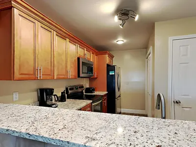a kitchen with wooden cabinets and a granite counter top at Edgewater Villa #2112 in Panama City Beach