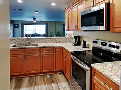 a kitchen with wooden cabinets and a stove top oven at Edgewater Villa #2112 in Panama City Beach