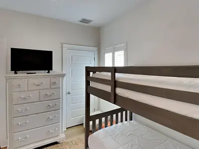 a bedroom with a bunk bed and a dresser with a television at Sun Kissed Memories in Panama City Beach