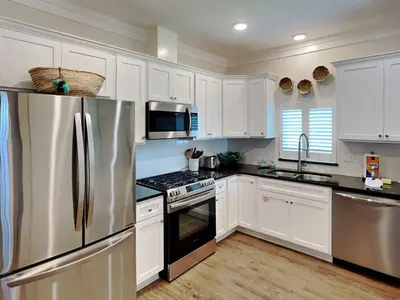 a kitchen with white cabinets and a stainless steel refrigerator at Sun Kissed Memories in Panama City Beach
