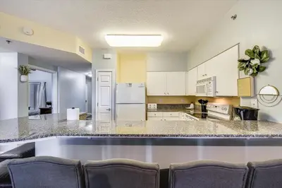 a large kitchen with a large counter with chairs at Shores of Panama 328 - Low Floor HUGE 3 BedroomBunk Room, Reserved Parking, condo in Panama City Beach