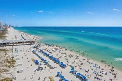 a group of people on a beach with umbrellas and the ocean at Shores of Panama 2025 - 1 Bedroom Bunks Sleeps 6, Reserved Parking, Free Fun! condo in Panama City Beach