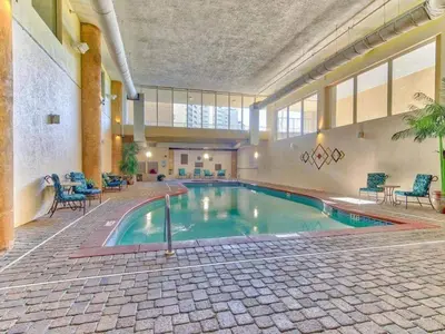 a swimming pool in a building with chairs and a table at Shores of Panama 2025 - 1 Bedroom Bunks Sleeps 6, Reserved Parking, Free Fun! condo in Panama City Beach