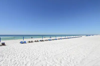 a beach with a line of chairs and the ocean at Shores of Panama 2327 - 1 BedroomBunks and Sleeper Sofa, Sunset View! Free Fun! condo in Panama City Beach